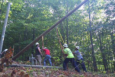 Workers setting a utility pole