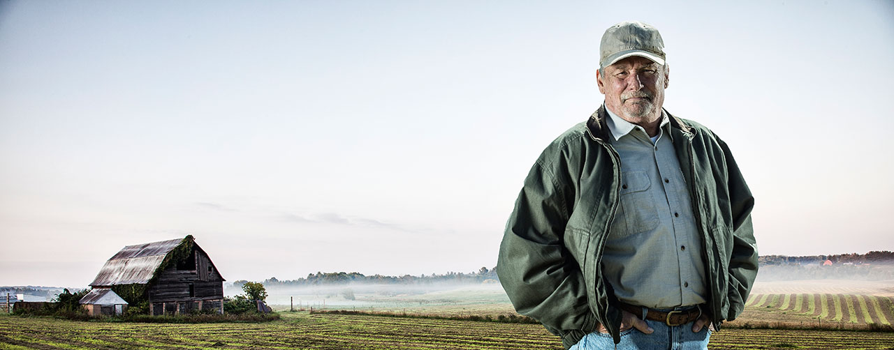 Farmer standing in front of barn and field